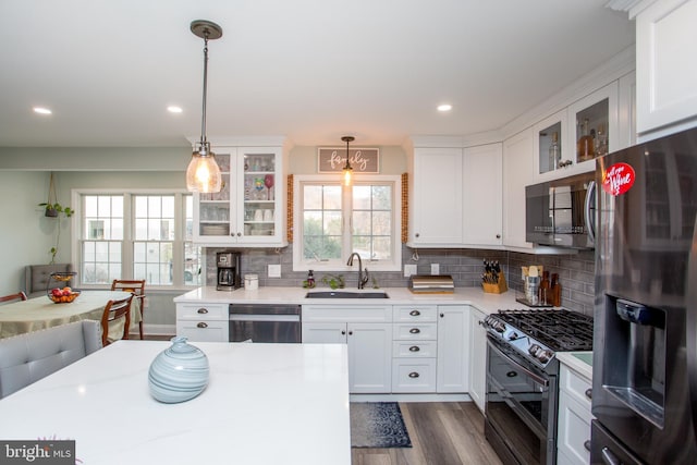 kitchen featuring dark wood-type flooring, sink, decorative light fixtures, white cabinetry, and stainless steel appliances