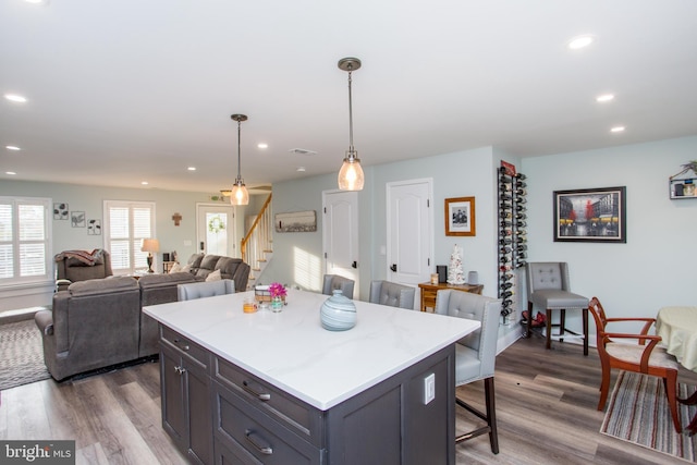 kitchen featuring dark hardwood / wood-style floors, a kitchen island, a kitchen bar, and decorative light fixtures