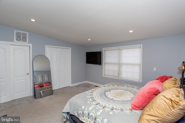 bedroom with light colored carpet and two closets