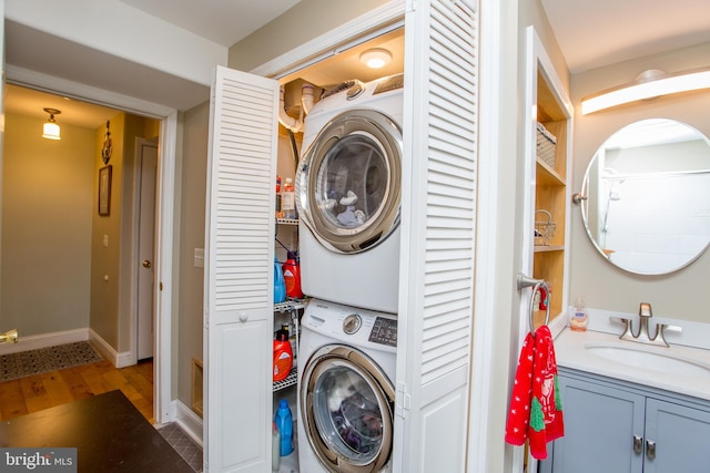 laundry room with sink, stacked washing maching and dryer, and hardwood / wood-style flooring