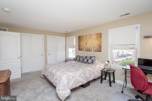 carpeted bedroom featuring two closets and multiple windows