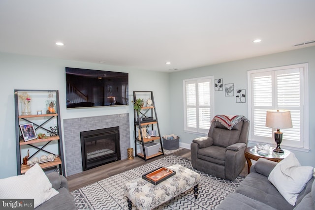 living room featuring a brick fireplace and light hardwood / wood-style flooring