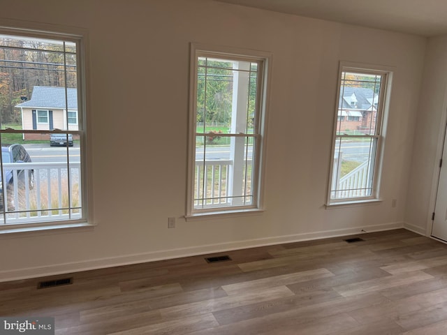 spare room with light wood-style floors, baseboards, and visible vents