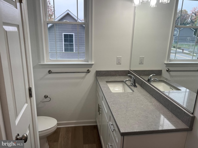 bathroom featuring toilet, wood finished floors, vanity, and baseboards