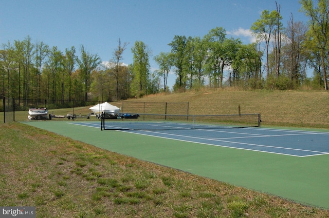 view of tennis court with fence and a yard