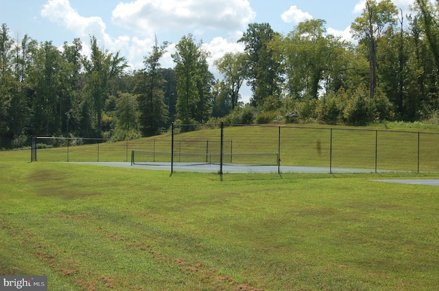 view of community with a rural view, a lawn, and fence