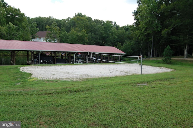 view of property's community with volleyball court, a wooded view, and a yard