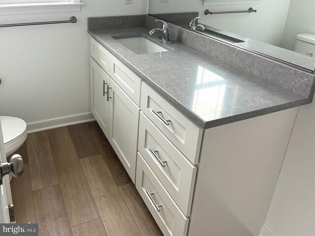 bathroom with toilet, baseboards, wood finished floors, and vanity