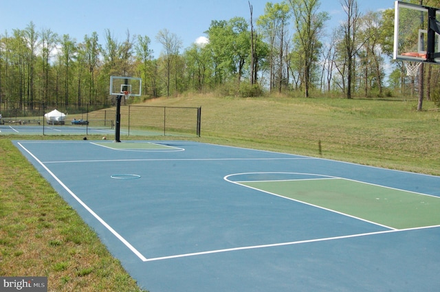 view of sport court featuring a tennis court, community basketball court, and a lawn