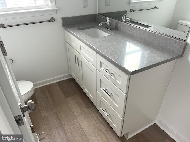 bathroom with toilet, baseboards, wood finished floors, and vanity