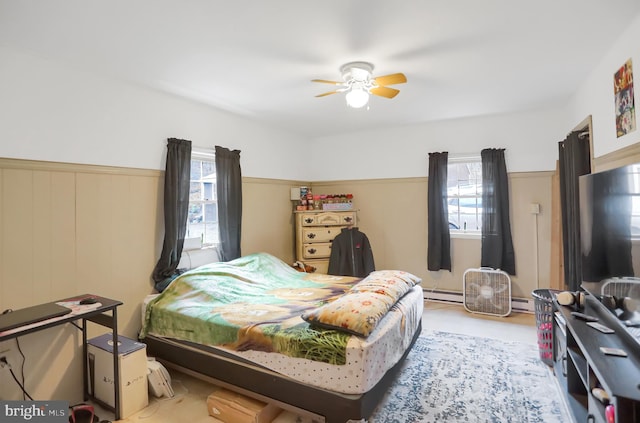 bedroom featuring a baseboard radiator, ceiling fan, and wooden walls