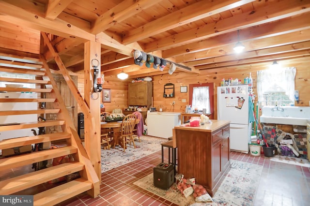 kitchen with sink, white refrigerator, wooden ceiling, a kitchen island, and wood walls