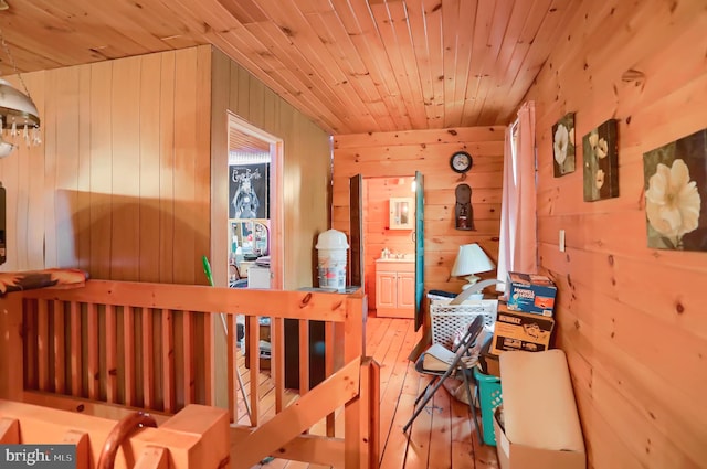 bedroom with wooden walls, sink, wooden ceiling, and hardwood / wood-style flooring