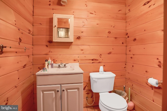 bathroom with vanity, wood walls, and toilet