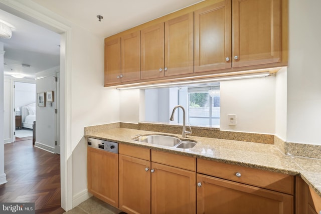 kitchen with dishwashing machine, light stone countertops, parquet flooring, and sink