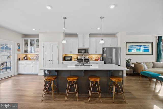 kitchen with white cabinets, sink, a breakfast bar area, decorative backsplash, and stainless steel appliances