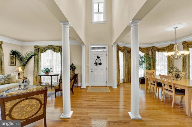 entrance foyer with light hardwood / wood-style flooring, ornamental molding, and an inviting chandelier