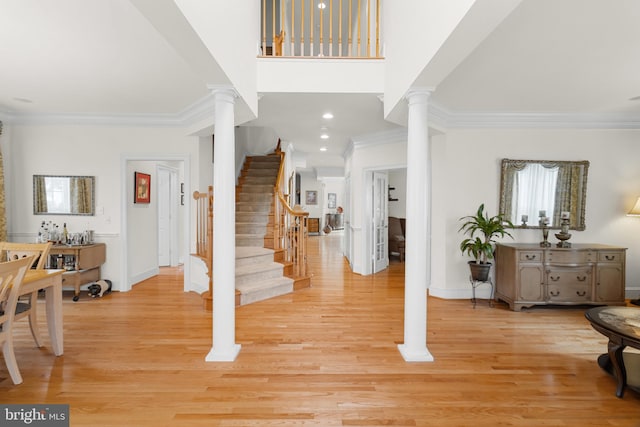 entrance foyer featuring crown molding, ornate columns, and light hardwood / wood-style floors