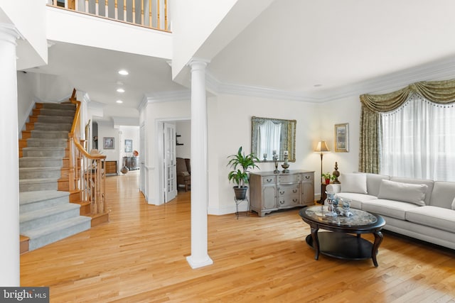 living room featuring decorative columns, crown molding, and light wood-type flooring