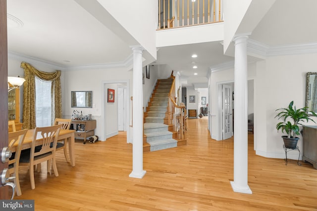 entrance foyer with ornamental molding, light hardwood / wood-style floors, and decorative columns