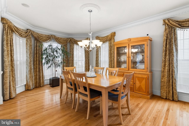 dining space with light hardwood / wood-style floors, ornamental molding, a chandelier, and a healthy amount of sunlight