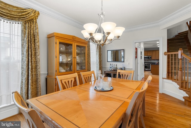 dining area featuring light hardwood / wood-style flooring, ornamental molding, and a chandelier