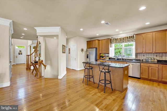 kitchen featuring a center island, stainless steel appliances, sink, light hardwood / wood-style flooring, and a breakfast bar area