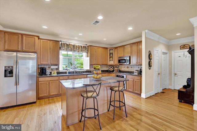 kitchen featuring a center island, a kitchen bar, sink, light hardwood / wood-style flooring, and appliances with stainless steel finishes