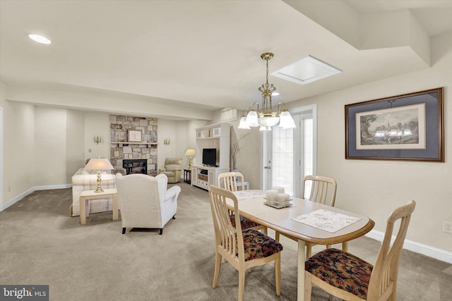 dining room featuring a skylight, light carpet, french doors, a fireplace, and a chandelier