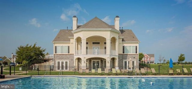 back of property with a patio area, a community pool, and french doors