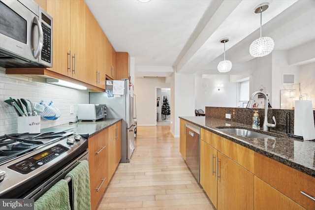 kitchen featuring decorative light fixtures, light hardwood / wood-style floors, dark stone countertops, and stainless steel appliances