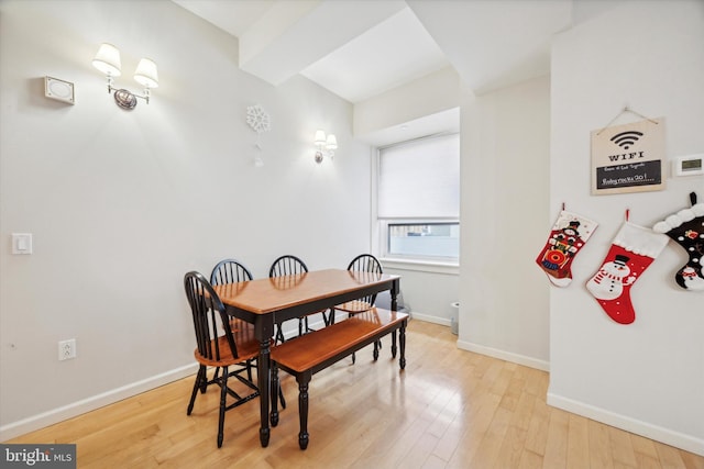 dining space featuring beamed ceiling and light hardwood / wood-style floors