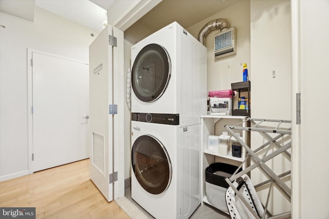 laundry area with stacked washing maching and dryer and hardwood / wood-style flooring