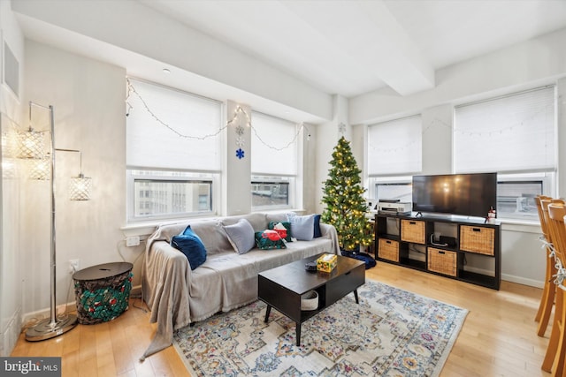 living room featuring beamed ceiling and light hardwood / wood-style floors