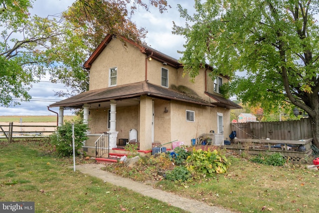 back of house with covered porch and a yard