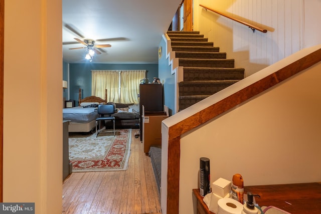 stairs featuring hardwood / wood-style floors and ceiling fan