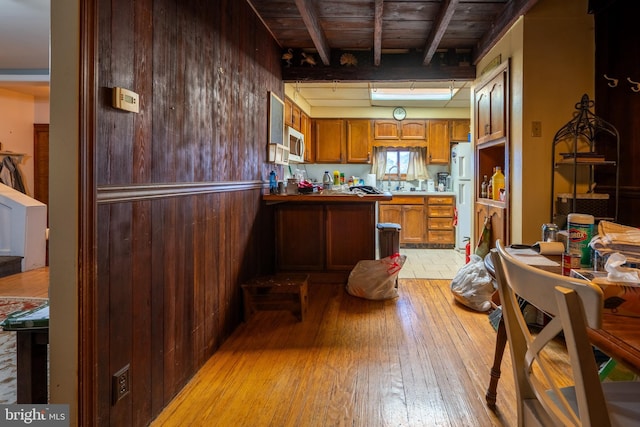 kitchen with beamed ceiling, white refrigerator, wooden ceiling, and wooden walls