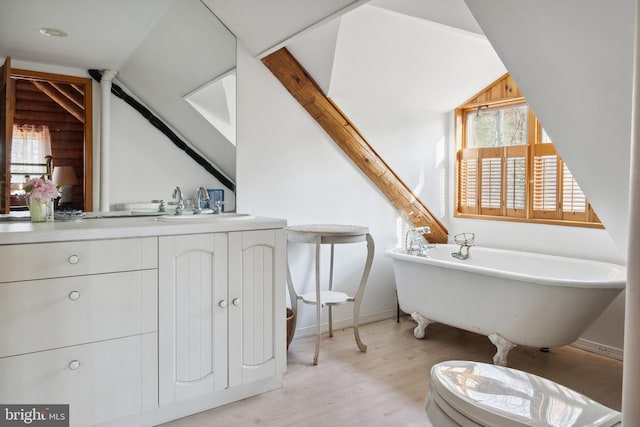 bathroom featuring hardwood / wood-style floors, lofted ceiling, plenty of natural light, and a tub