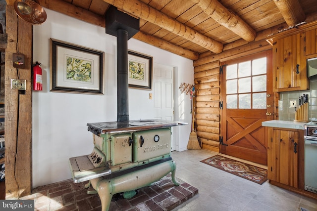 interior space with beamed ceiling, wooden ceiling, rustic walls, and a wood stove