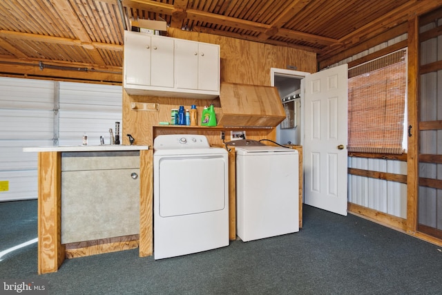 washroom with dark carpet, cabinets, sink, wooden walls, and separate washer and dryer