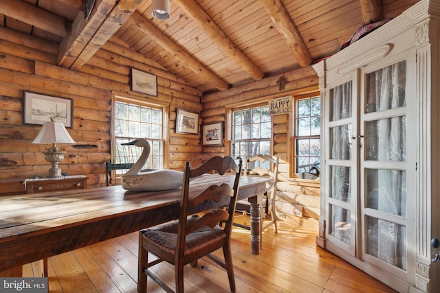 dining area with vaulted ceiling with beams, plenty of natural light, and log walls