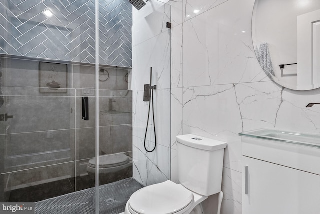 bathroom featuring a shower with door, vanity, tile walls, and toilet