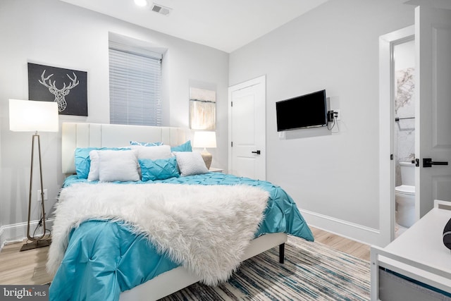 bedroom with ensuite bathroom and light hardwood / wood-style flooring