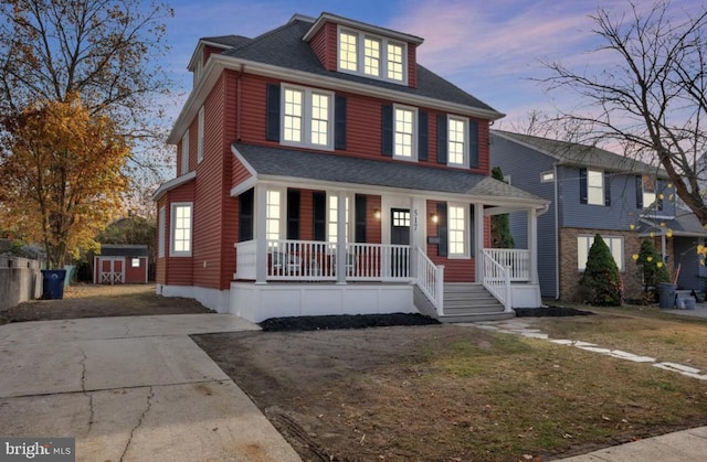 view of front of house featuring covered porch, a yard, and a storage shed