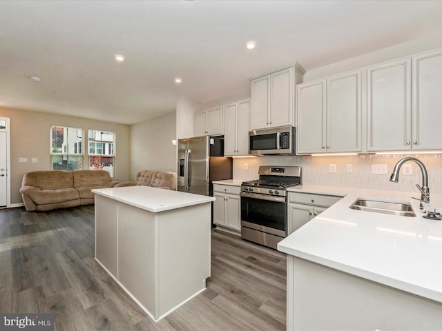 kitchen with hardwood / wood-style floors, stainless steel appliances, a kitchen island, and sink