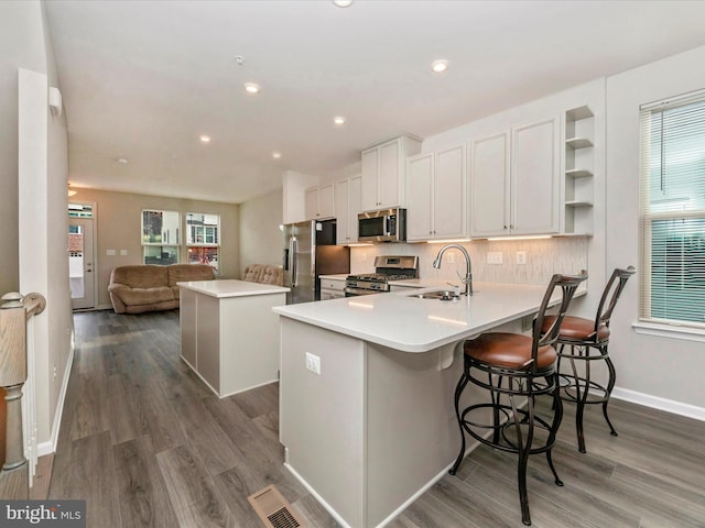 kitchen featuring a breakfast bar, stainless steel appliances, sink, white cabinets, and a center island