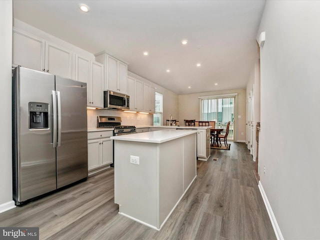 kitchen with light hardwood / wood-style floors, a kitchen island, white cabinetry, and appliances with stainless steel finishes