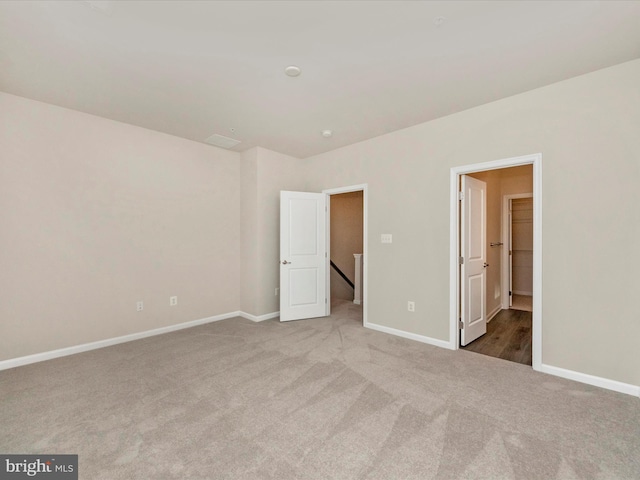 unfurnished bedroom featuring ensuite bath and light colored carpet