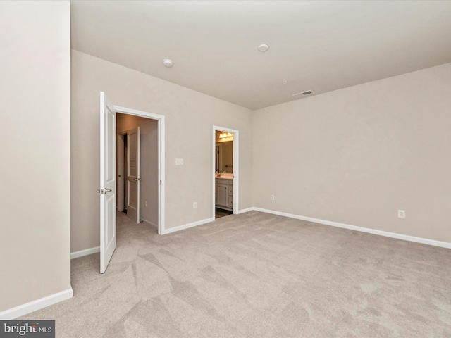 unfurnished bedroom with connected bathroom and light colored carpet