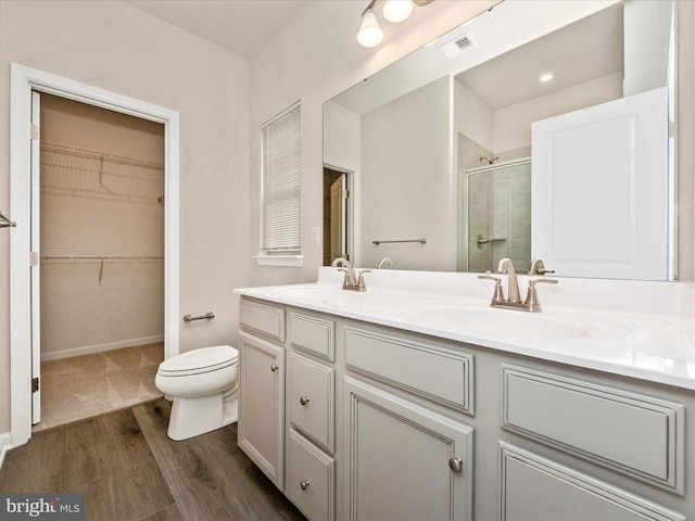 bathroom with walk in shower, hardwood / wood-style floors, vanity, and toilet